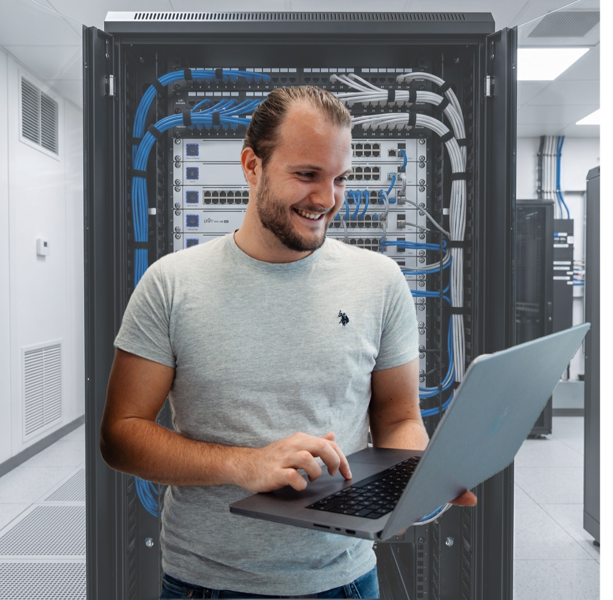 Christoph Harrison von Harrison Networks, am Laptop vor einem sauber gepatchten Netzwerkschrank