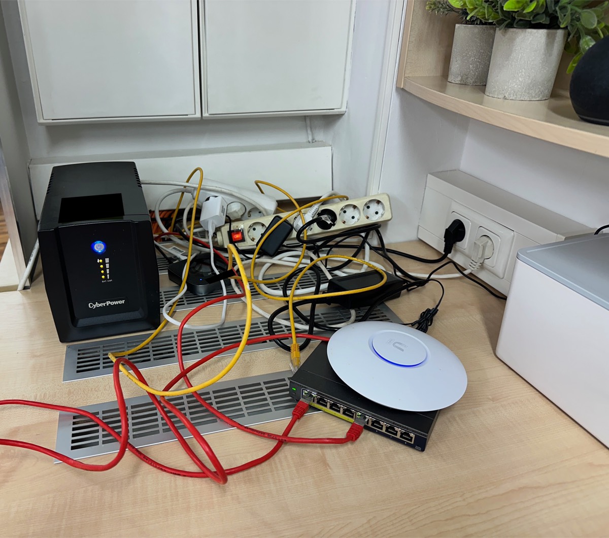 Vorher: sogar ein UniFi Access Point war schon da. Er lag eingeschaltet flach auf einem Switch im Empfangsbereich, statt an der Decke zu hängen, daneben USV und Kabelknäuel.
